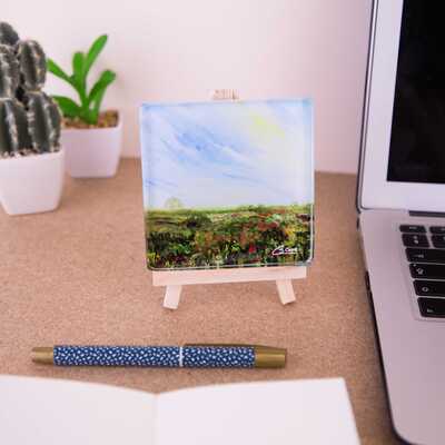 On a mini easel is a glass coaster of the painting Heathlands