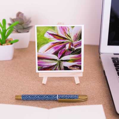 A mini easel holding a ceramic coaster of the painting Lilies