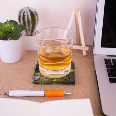 A whisky tumbler on top of the glass coaster of Tranquil dreams