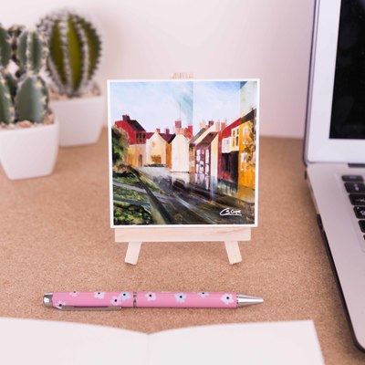 On a mini easel is a ceramic coaster of the painting Greatham after the rain