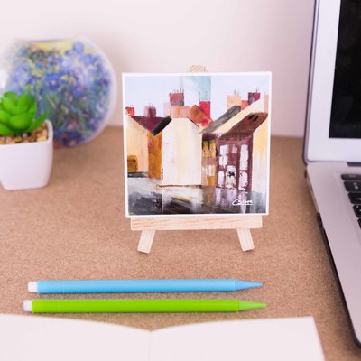 On a mini easel is a ceramic coaster with a close up of the painting 'Greatham after the rain'