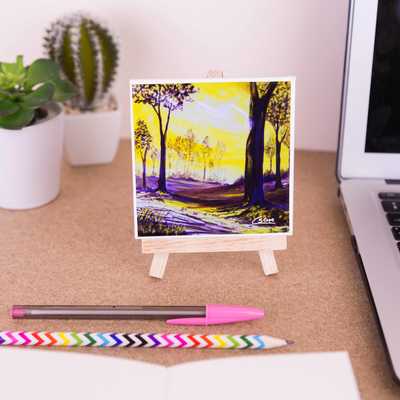 On a mini easel is a ceramic coaster of the painting In to the golden glade
