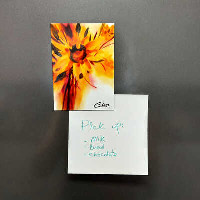 A magnet of Sunflower awakening holding a note on a graphine coloured fridge
