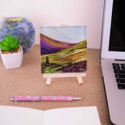 On a mini easel is a glass coaster of the painting The Sentinel