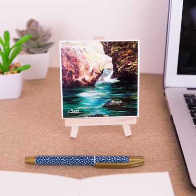 On a mini easel is a ceramic coaster of Through the rocks