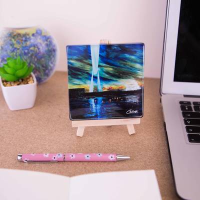 On a mini easel is a glass coaster of the painting Transporter Bridge at night