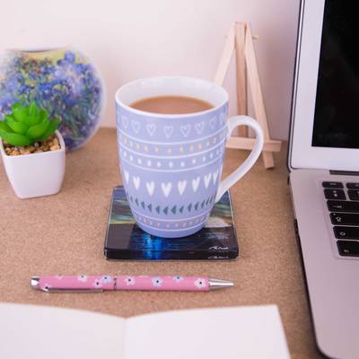 Cup on top of a glass coaster on a desk