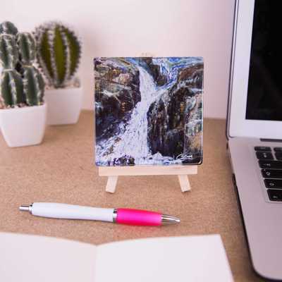 On a mini easel is a glass coaster of the painting Waterfall